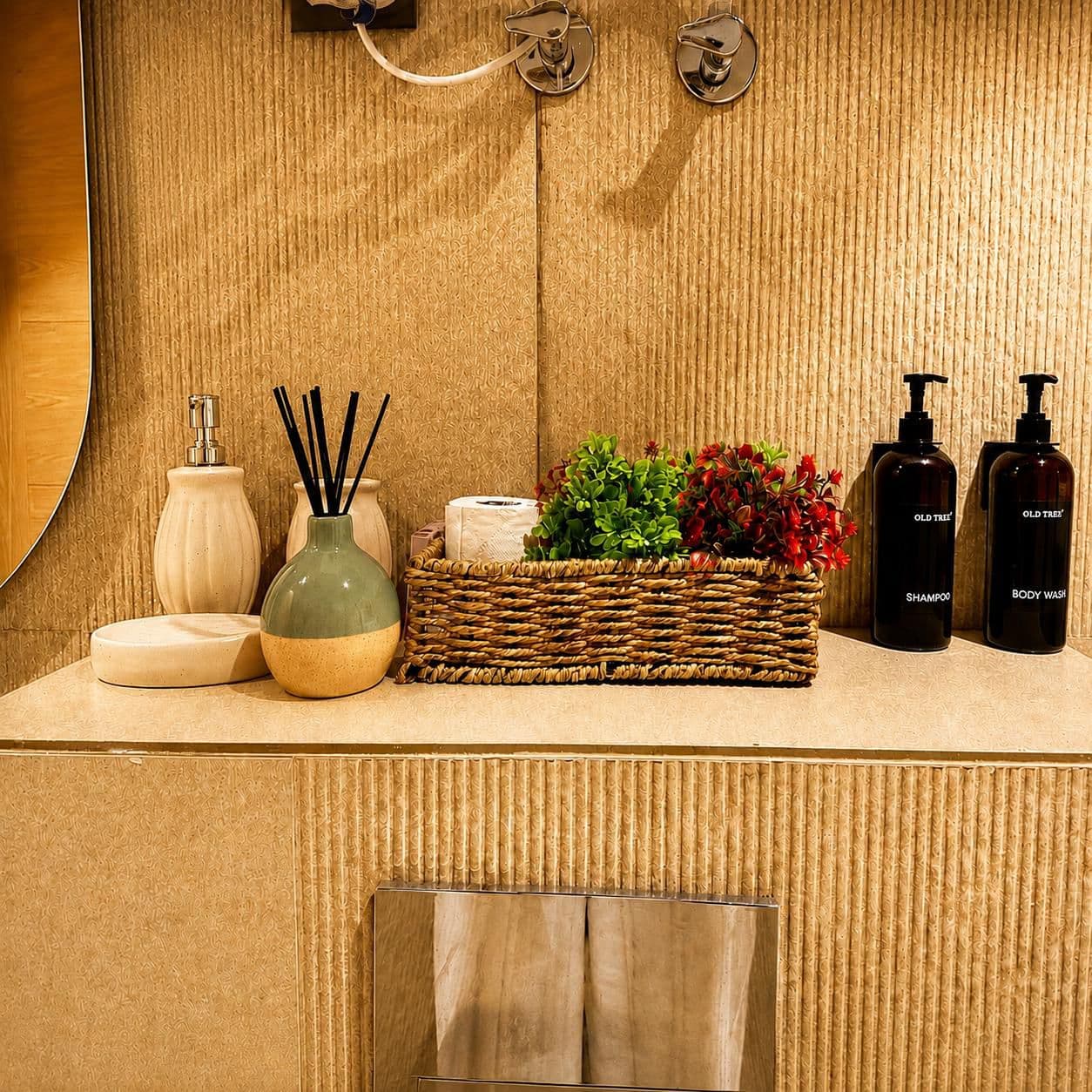 Bathroom counter styled with a reed diffuser, amenities, and greenery
