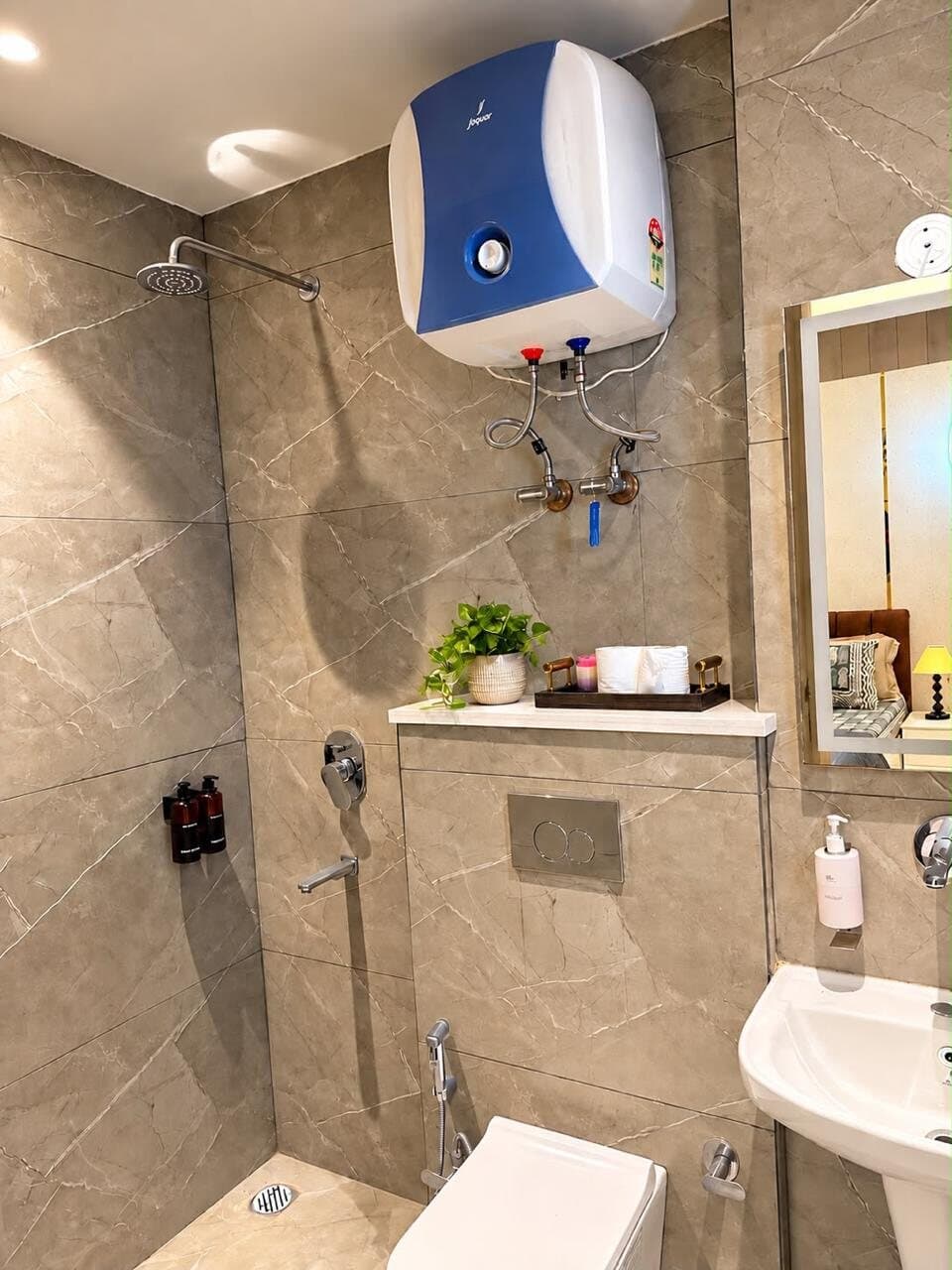 Walk-in shower with a rain shower head, water heater, and toiletries on a marble ledge