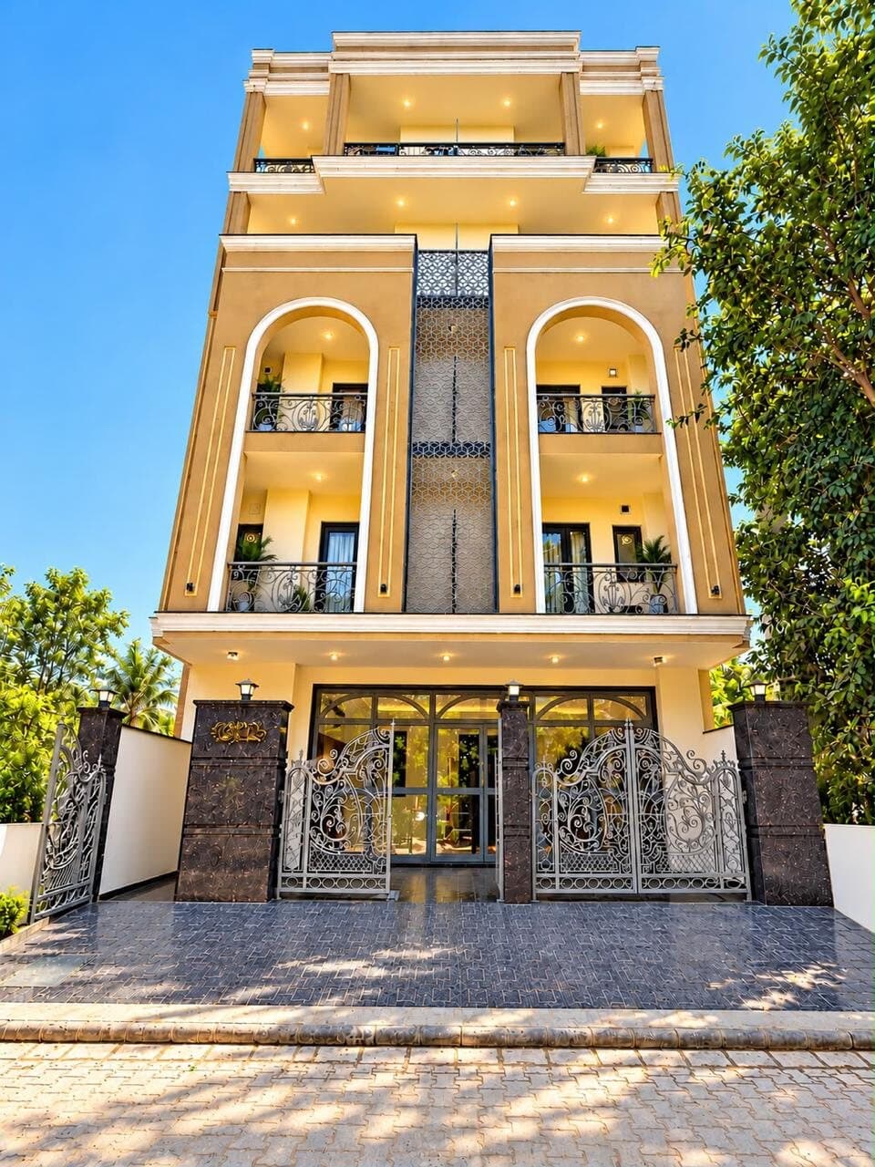 Cream-and-gold building facade with arched balconies and ornate wrought-iron gates under a blue sky
